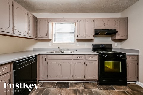 A kitchen with a black oven and pink cabinets.