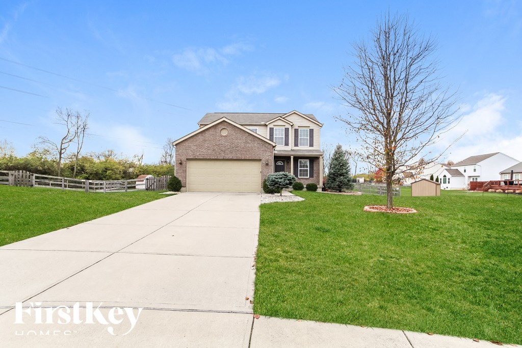 A house with a garage and a tree in front of it.