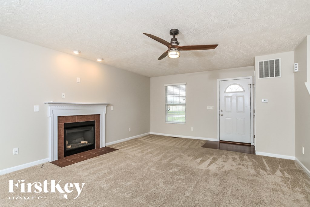 A spacious room with a fireplace and a ceiling fan.