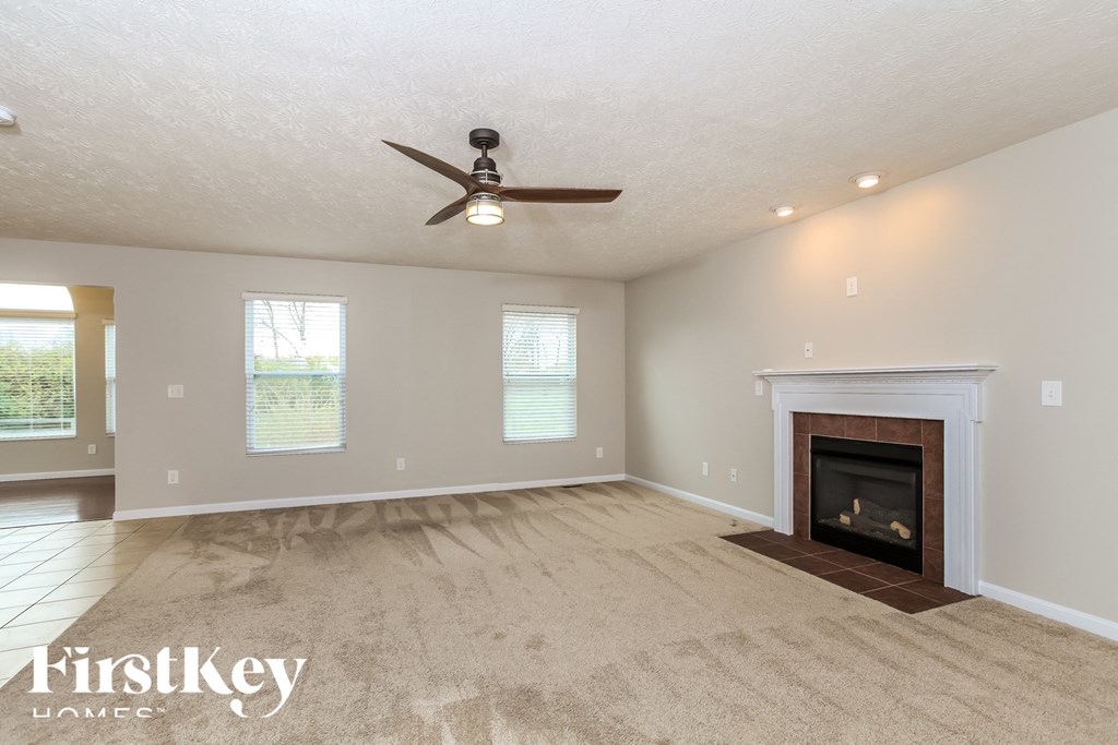 A spacious room with a fireplace and a ceiling fan.
