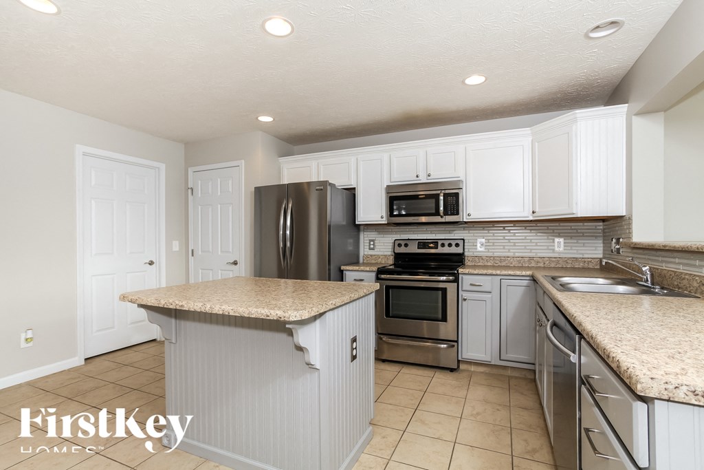 A kitchen with a granite countertop and stainless steel appliances.