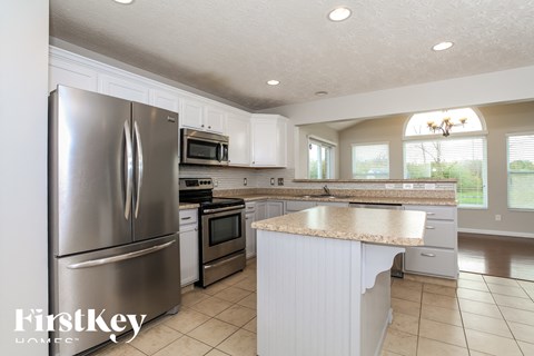 A kitchen with a stainless steel refrigerator and white cabinets.