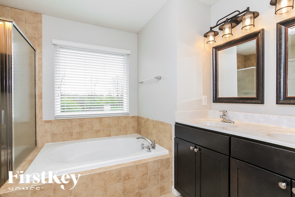 A bathroom with a tub, sink, and mirror.