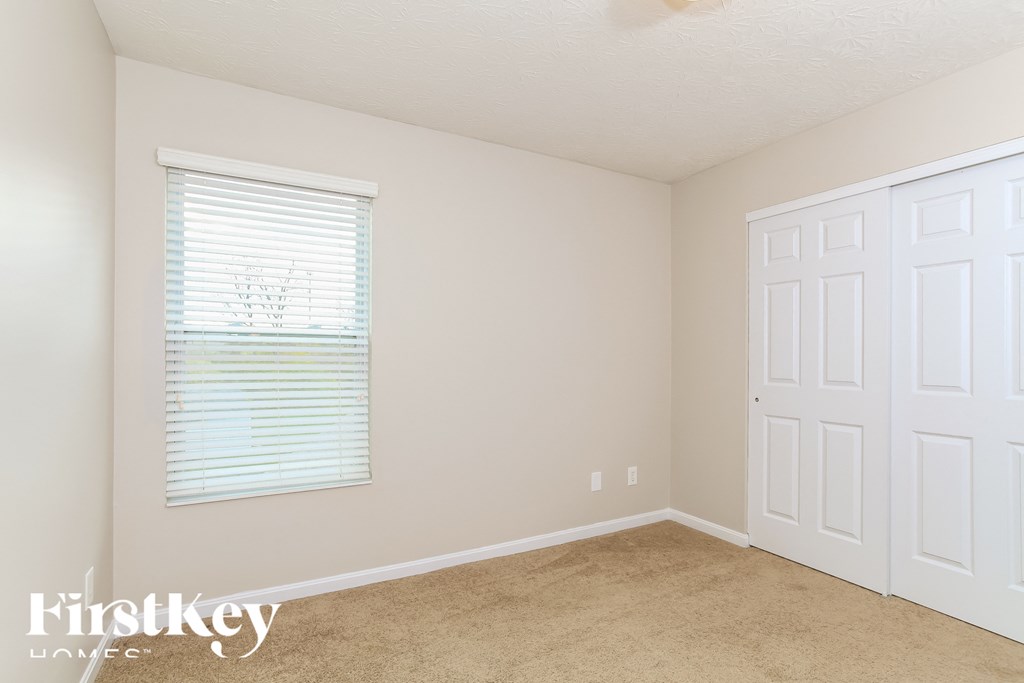 A room with a white door and a window with blinds.
