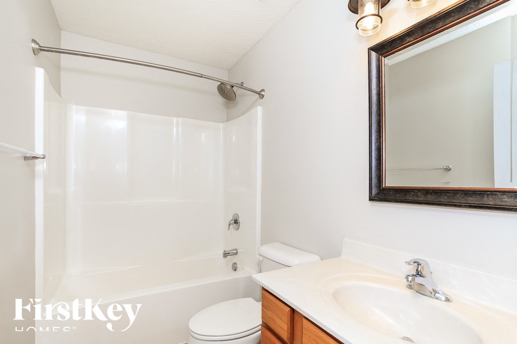 A white bathroom with a toilet, sink, and shower.