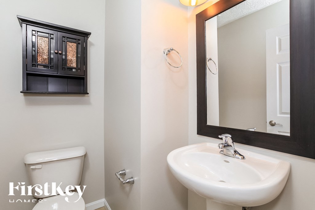 A bathroom with a white sink and a cabinet above it.