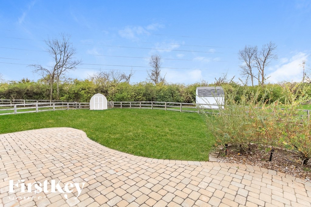 A brick walkway leads to a white circular structure in a grassy field.