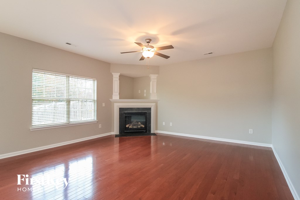 A living room with a fireplace and a ceiling fan.