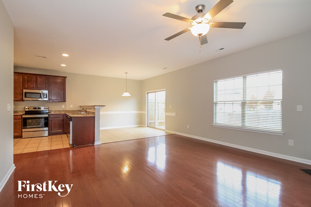 A spacious living room with wooden floors and a ceiling fan.