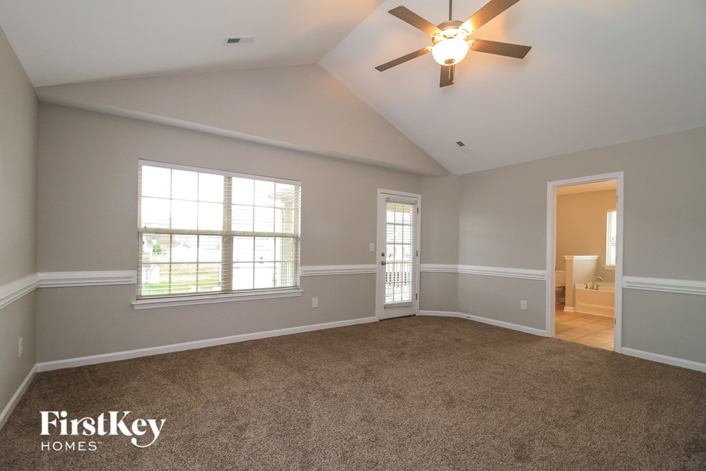 A spacious room with a ceiling fan and two windows.