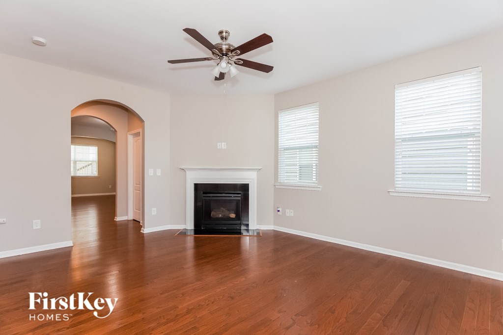 A spacious living room with a fireplace and a ceiling fan.