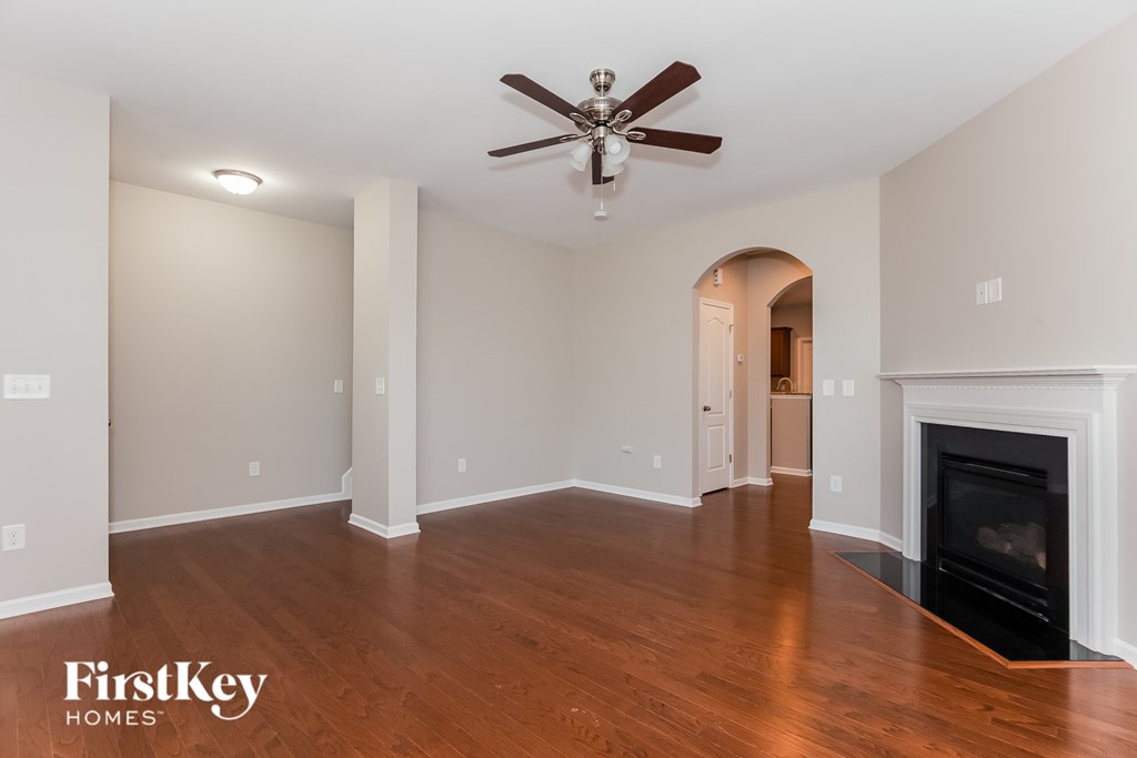 A spacious living room with a fireplace and a ceiling fan.