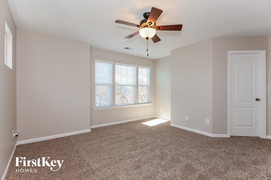A spacious room with a ceiling fan and carpeted floor.
