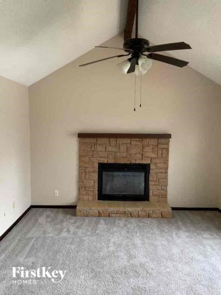 a living room with a brick fireplace and a ceiling fan