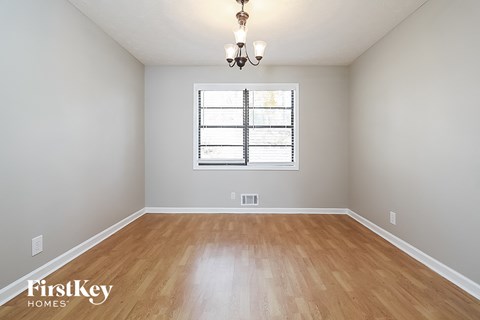 A room with wooden flooring and a window with blinds.