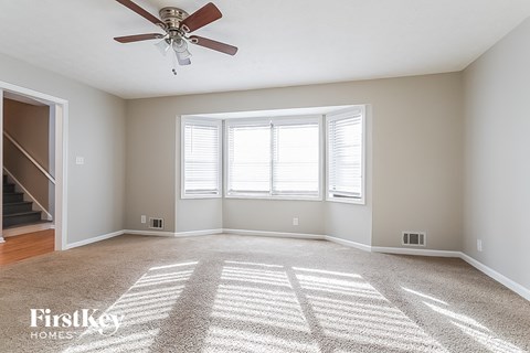 A spacious room with a carpeted floor and a ceiling fan.