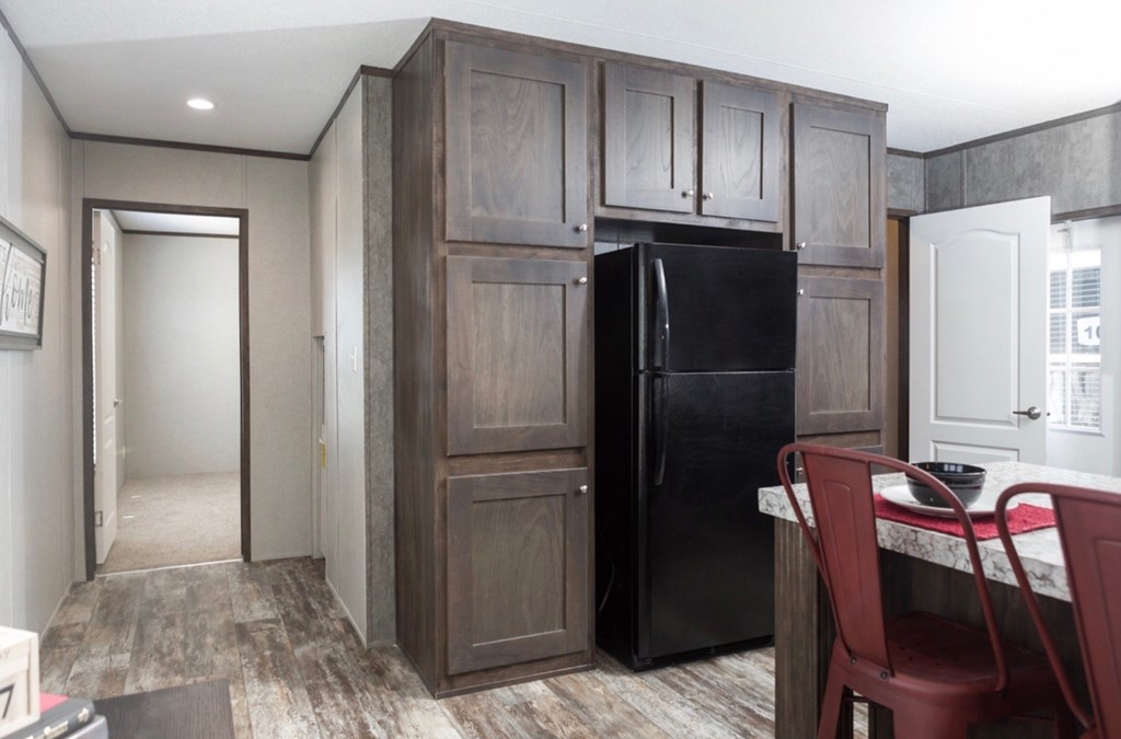 a kitchen with a black refrigerator and wooden cabinets