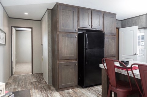 a kitchen with a black refrigerator and wooden cabinets