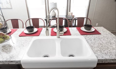 a kitchen sink with two bowls and two cups on a counter top