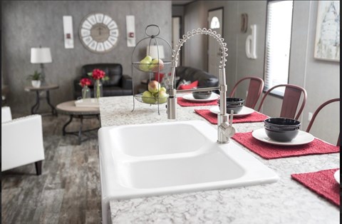 a kitchen with a sink and a dining room with a table and chairs