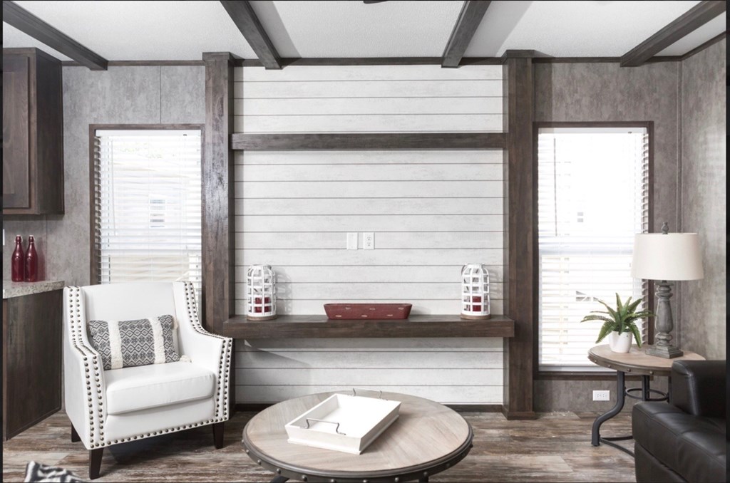 a living room with a chair and a table and a wall with two windows