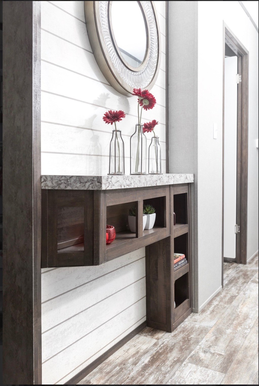a hallway with a mirror and a shelf with vases