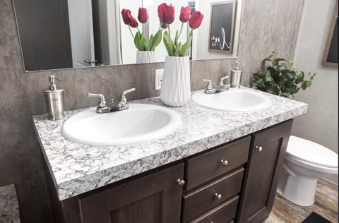 a bathroom with two sinks and a vase with red tulips