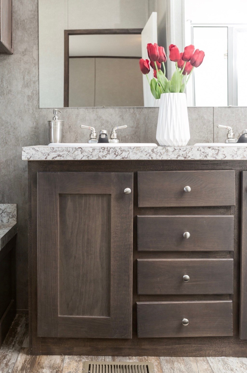 a bathroom sink with a vase of tulips on it