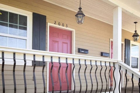 a porch with red chairs and a pink door