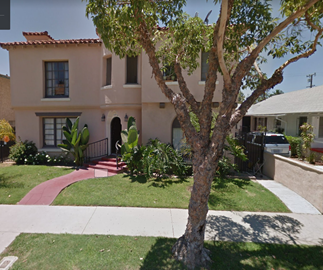 a house with a tree and a sidewalk in front of it
