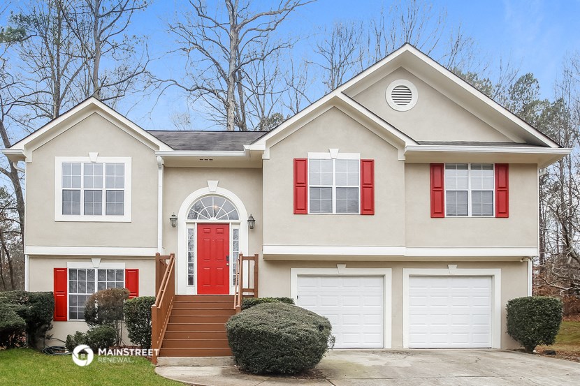 a tan house with red shutters and a red door
