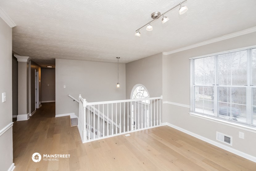 the living room and dining room of a home with a staircase and a large window