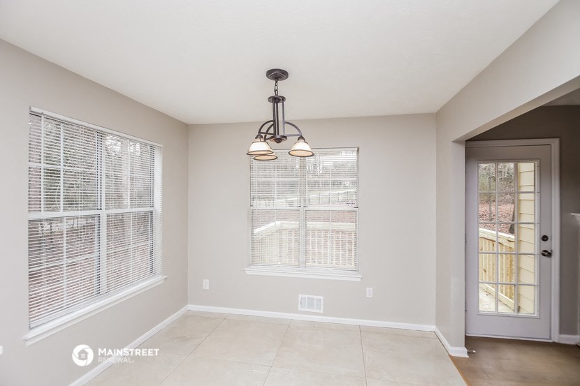 the living room of an empty home with two windows and a door