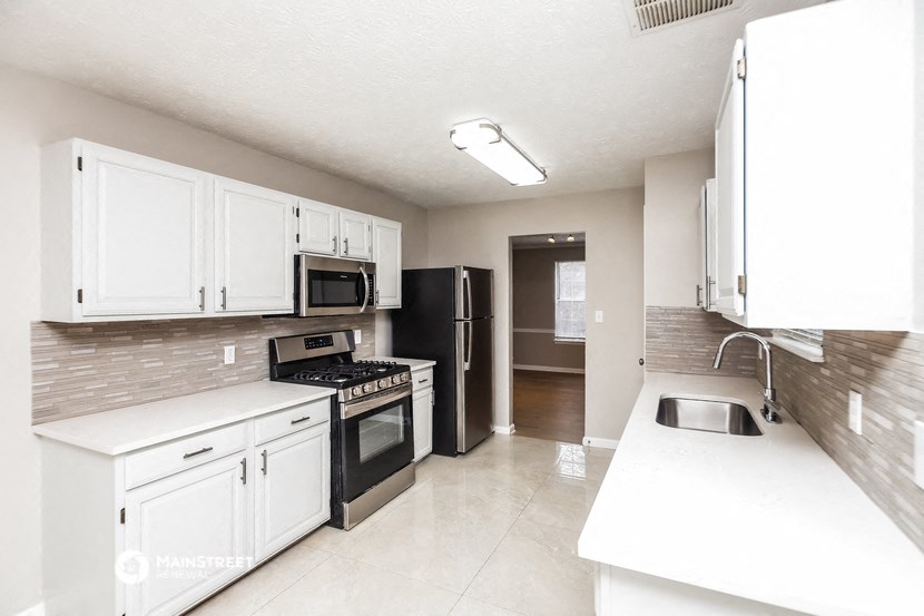 an empty kitchen with white cabinets and black appliances