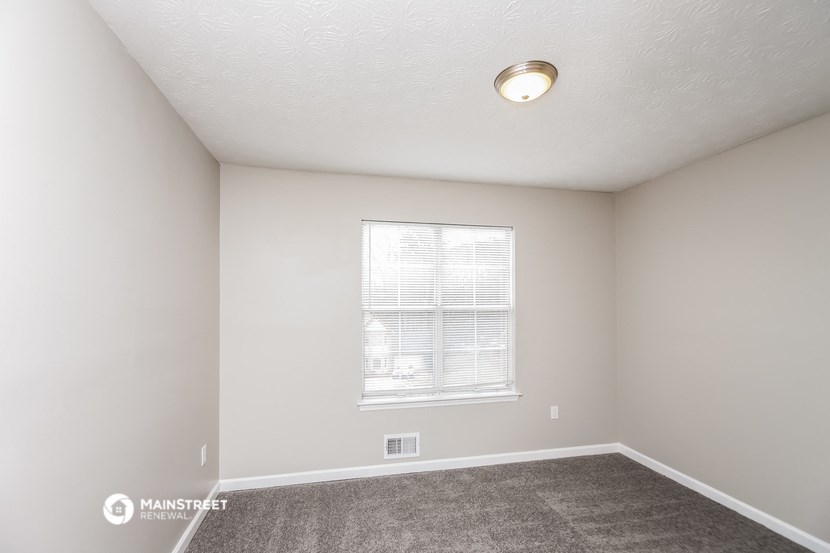 the spacious living room of a manufactured home with carpet and a window