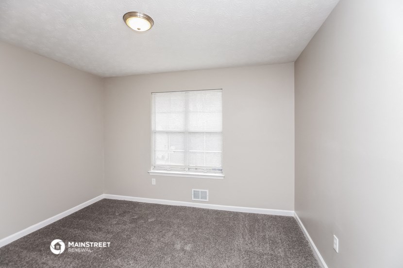the spacious living room of a manufactured home with carpet and a window