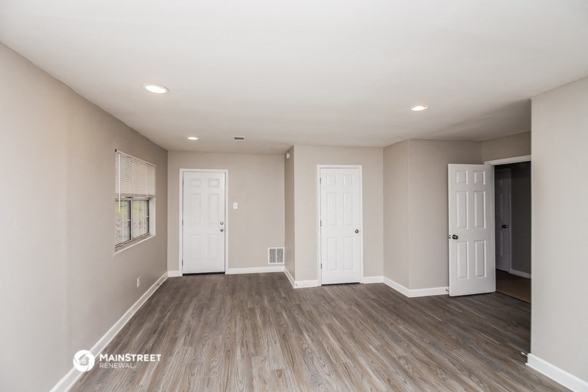 the living room of a new home with white doors and wood flooring