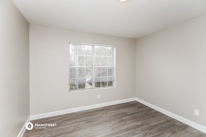 the living room of an apartment with wood flooring and a window