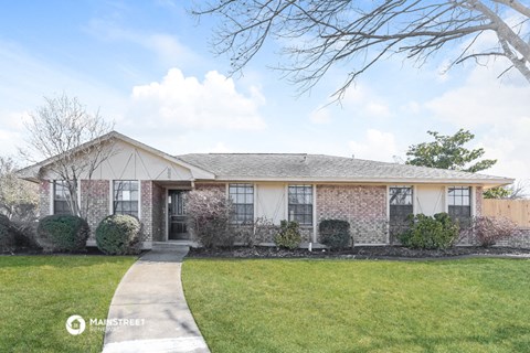 a brick house with a lawn and a sidewalk