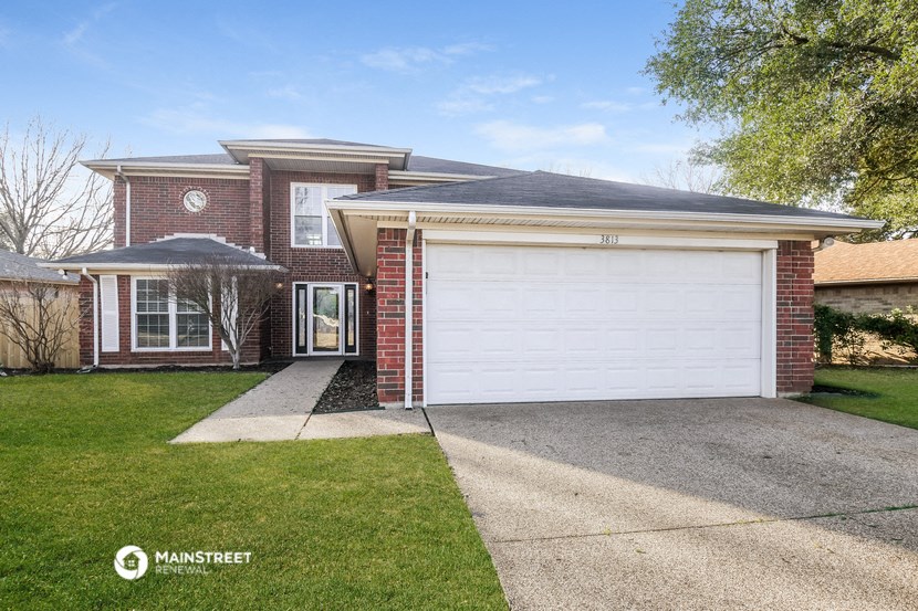 a white garage door in front of a brick house