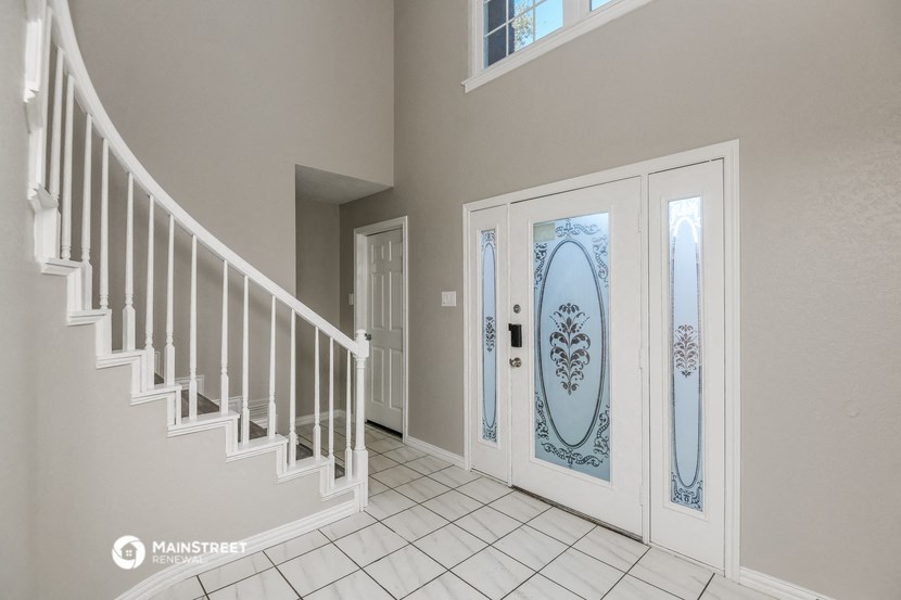 the entryway of a house with white doors and a staircase