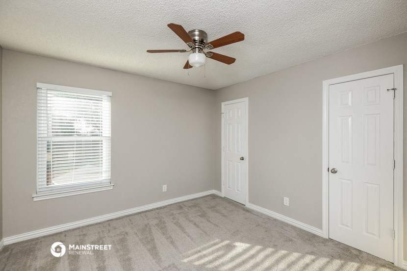 the bedroom has a ceiling fan and a door to the closet