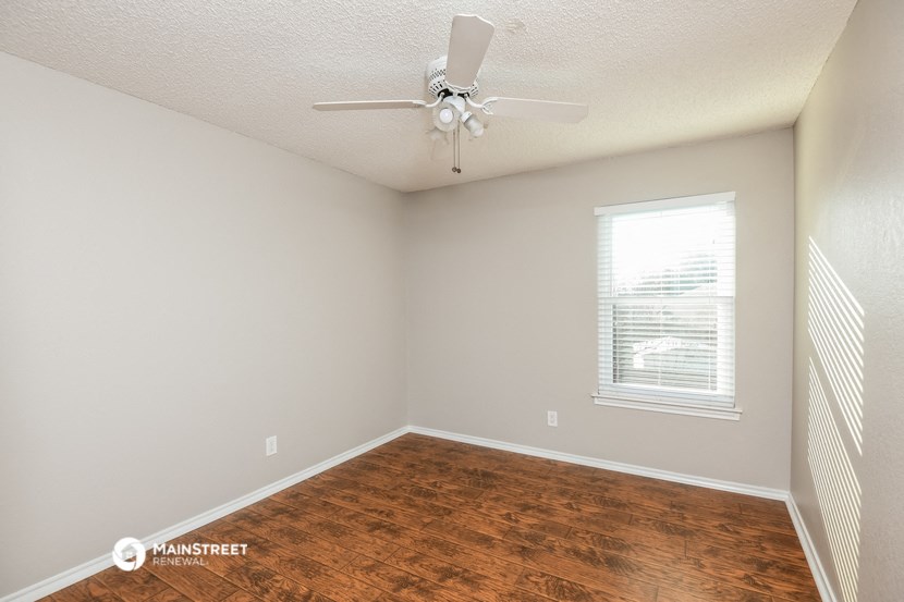 an empty room with a ceiling fan and a window
