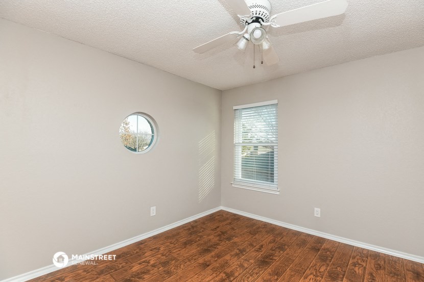 an empty room with a ceiling fan and a window