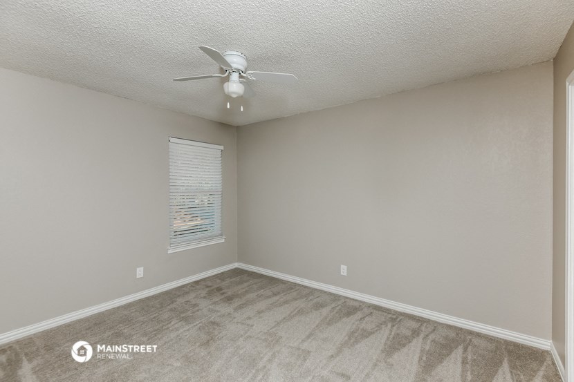 an empty room with a ceiling fan and a window