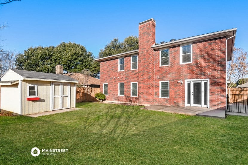 a brick house with a yard and a white shed