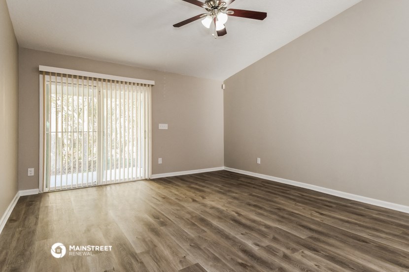 the spacious living room with wood flooring and a ceiling fan