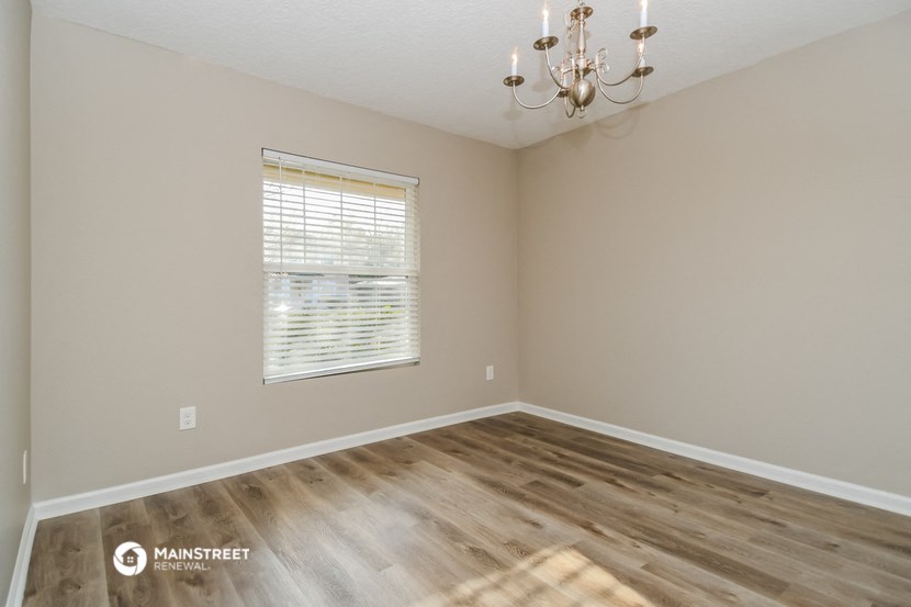 the spacious living room with wood flooring and a window