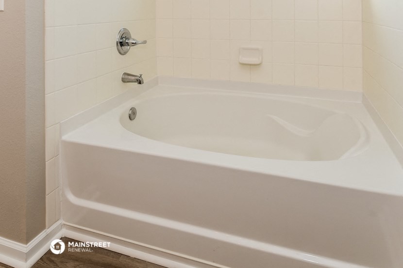 a white bath tub in a white tiled bathroom
