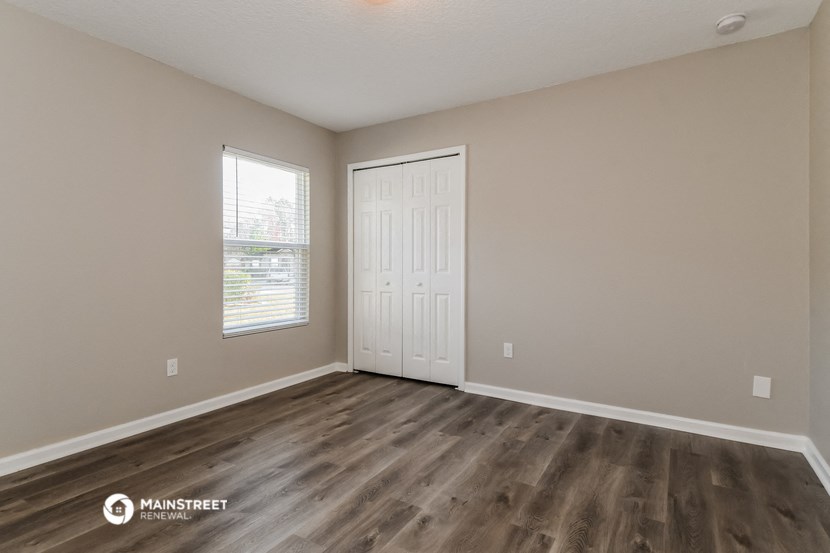 the spacious living room with wood flooring and a white door